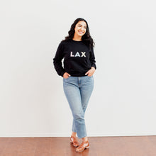 Load image into Gallery viewer, Woman is wearing a black crewneck with LAX written on the front in colourful letters
