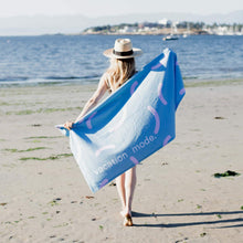 Load image into Gallery viewer, Woman is holding a blue and pink beach towel with words &#39;vacation mode&#39; witten on it
