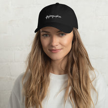 Load image into Gallery viewer, Model is wearing a black baseball cap that has a low profile with an adjustable strap and curved visor.
